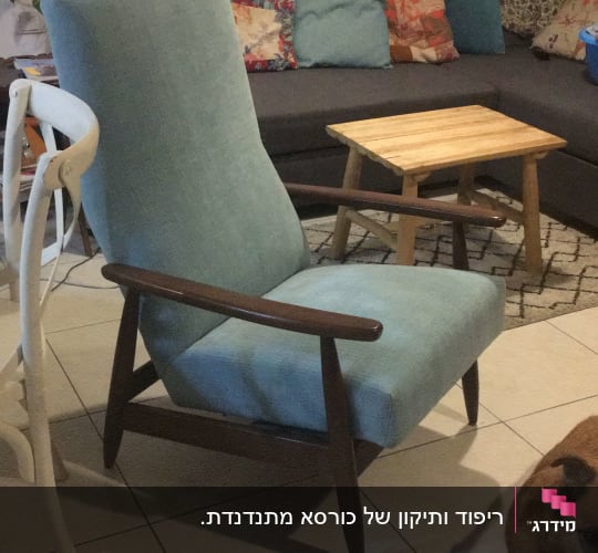 כורסה מרופדת בבד כחול בהיר עם מסגרת עץ כהה